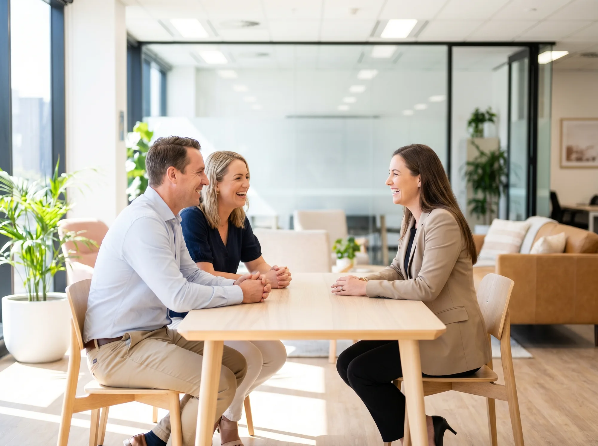 A couple talking happily with their solicitor at a bright table